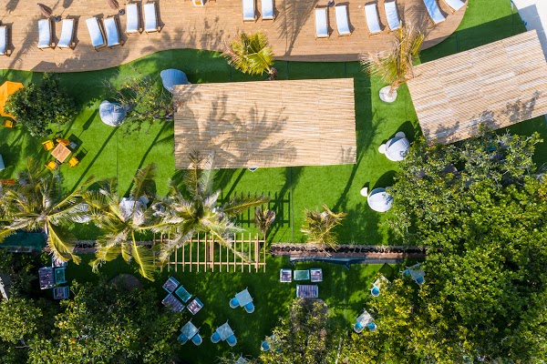 Aerial view of You & Me Maldives grounds with timber deck, sun loungers, palm trees, shaded pavilions and lawn seating, Raa