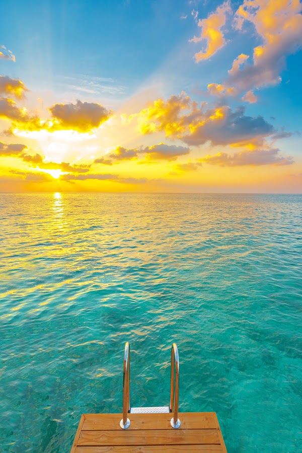 Wooden deck with swim ladder over turquoise lagoon at sunset, You & Me Maldives, Raa
