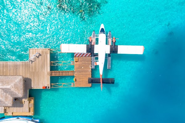 Aerial view of a white seaplane moored at a wooden jetty over turquoise lagoon, You & Me Maldives, Raa