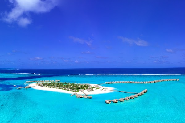 Aerial view of You & Me Maldives island with overwater villas, white sand beach and turquoise lagoon in Raa
